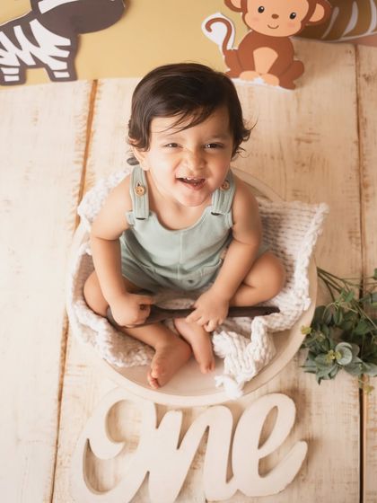 A top-down view of the birthday boy's infectious smile during his jungle-themed cake smash session.