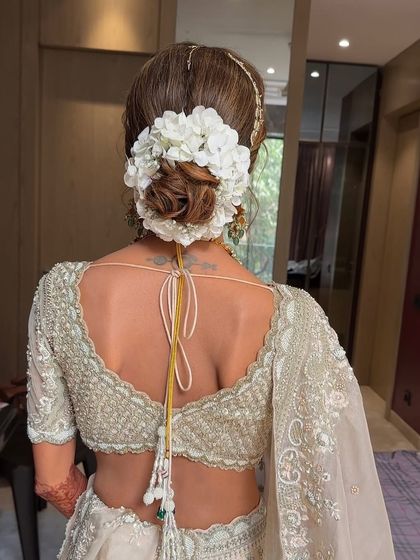 A clean and classic bridal bun adorned with a simple yet elegant arrangement of white flowers. This minimalist approach is perfect for brides who want a sophisticated look that doesn't overpower their features or attire.