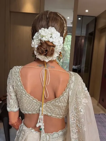 A clean and classic bridal bun adorned with a simple yet elegant arrangement of white flowers. This minimalist approach is perfect for brides who want a sophisticated look that doesn't overpower their features or attire.