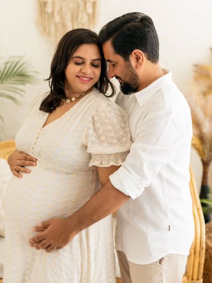 A tender embrace between a couple, their hands together on the baby bump, surrounded by the warm decor of our studio.