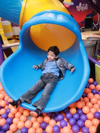 A perfect action shot of a young boy enjoying the ride down our multi-colored roller slide, landing safely in the soft ball pit below.
