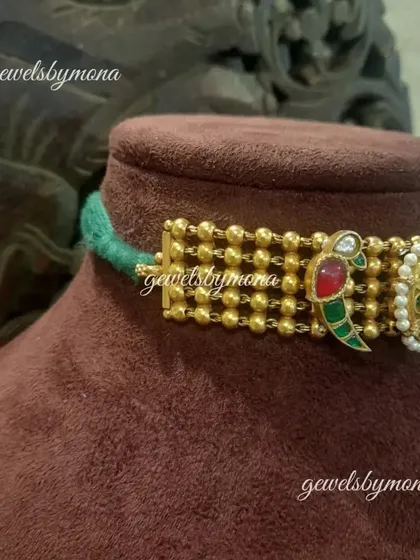 Another angle of the Dakshinaya choker, highlighting the craftsmanship of the gold beading and the vibrant enamel work on the parrot motifs.