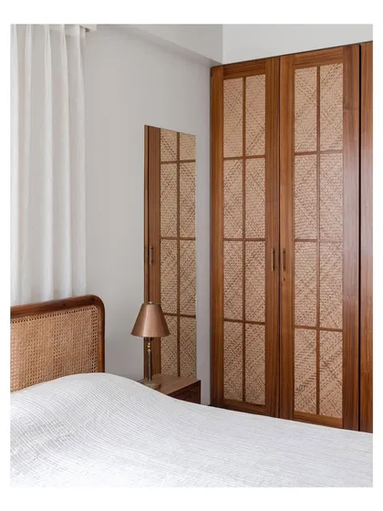 A closer look at the wardrobe with woven rattan doors. The natural texture adds a tactile quality to the room, making functional storage a beautiful feature.