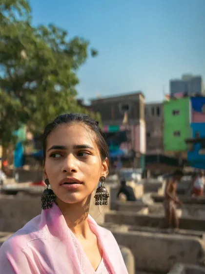 A profile shot looking away from the camera, giving a sense of being lost in thought amidst the daily work of the ghat.