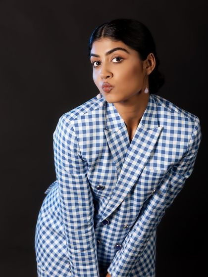 A playful and quirky expression that instantly shows personality. The classic gingham suit against a stark black background creates a fun and memorable portrait.