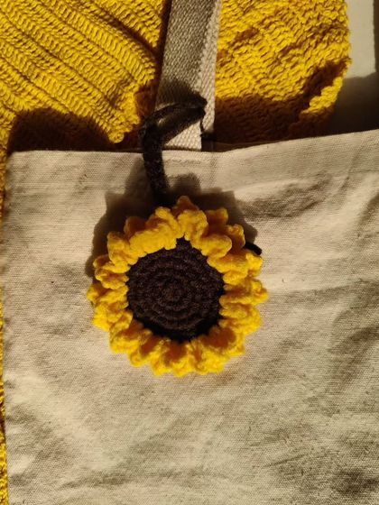 The sunflower bag charm attached to a canvas tote, showing how it can instantly elevate a simple bag.