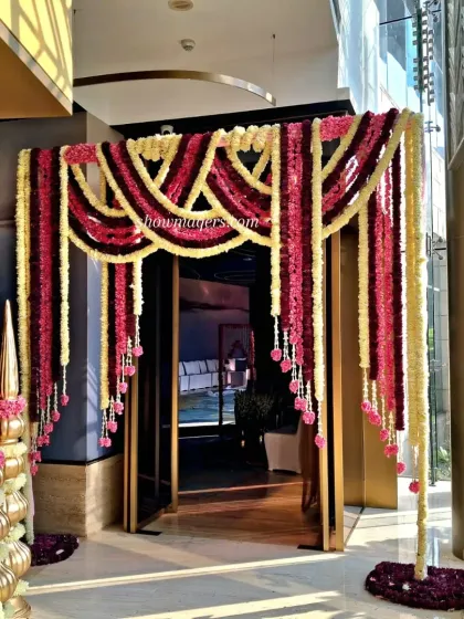 A grand floral entrance gate made with cascading garlands of red and yellow flowers, creating a dramatic and traditional welcome.