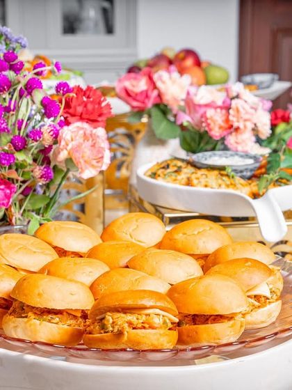 A platter of our chicken sliders, beautifully arranged amidst floral decor as part of a grazing table.