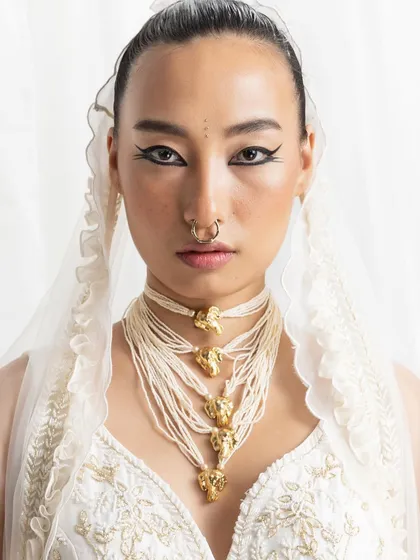 A powerful close-up from the Seema Thukral campaign. This shot highlights the intricate, multi-layered pearl and gold necklace against a delicate white outfit, complemented by bold, graphic eyeliner, showcasing a blend of traditional and modern beauty.