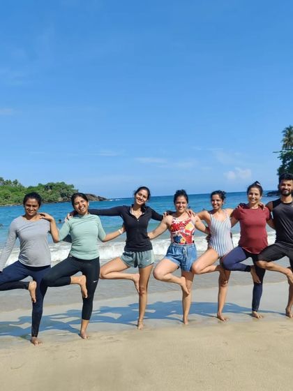 Finding balance and friendship on the shores of Sri Lanka. A playful moment of Vrikshasana, or tree pose, with the blue ocean as our backdrop.