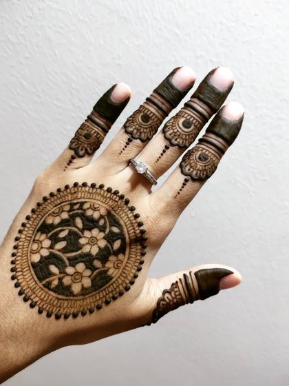 An intricate mandala with a floral vine fill, surrounded by detailed finger work.