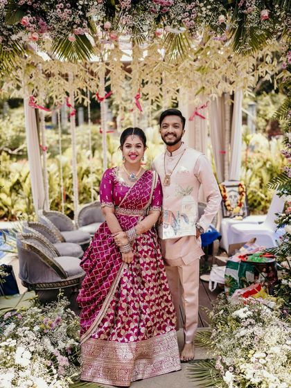 A classic portrait of the couple posing under a floral arch at their engagement.