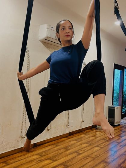 A student preparing for an aerial sequence, demonstrating focus and control while using the silk for support.