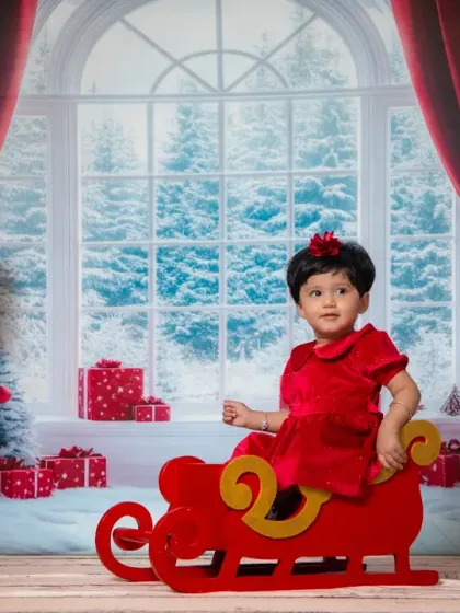 A little girl in a red dress, ready to ride in Santa's sleigh.