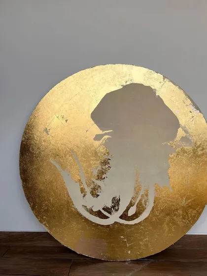 The beginning of a circular art piece for a Goa hotel. The canvas is covered in gold leaf, with the silhouette of a jellyfish masked out, creating a negative space that will soon be filled with color.