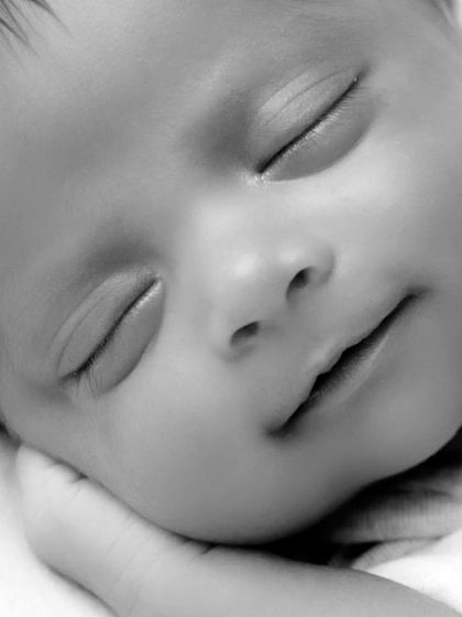 A macro shot in black and white of a newborn's face, highlighting the soft curve of their cheek and lips. This is my favorite part of newborn shoots, capturing the little details that matter most.