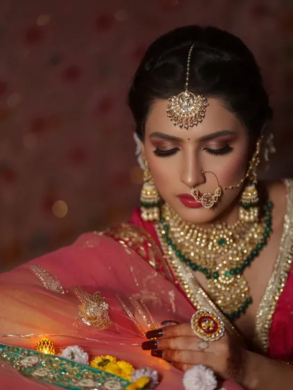 A close-up of a timeless bridal look. This bride's radiant makeup, featuring defined eyes and traditional jewellery, perfectly complements her classic red lehenga. This is the kind of elegance that never goes out of style.