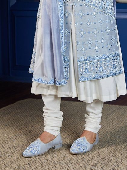 A focus on the lower half of the ensemble, showing the detailed embroidery on the custom mojris that perfectly match the sherwani.
