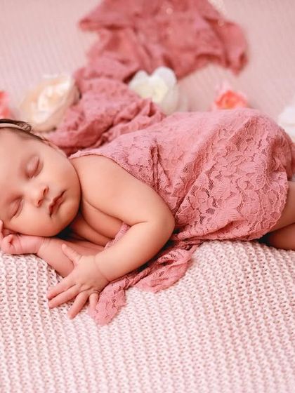 Draped in delicate pink lace, this little princess is sleeping peacefully. This simple beanbag pose is enhanced by the texture of the fabric and surrounding flowers.