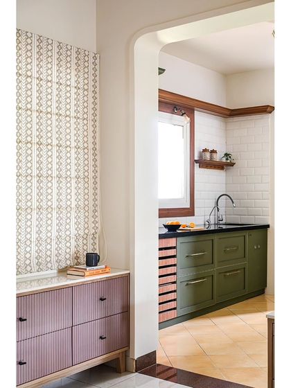 This kitchen was transformed from a dark, cramped space into a bright and classic room. I used a deep green laminate for the cabinets with antique handles, and a fluted cabinet in a dusty pink adds a pop of color.