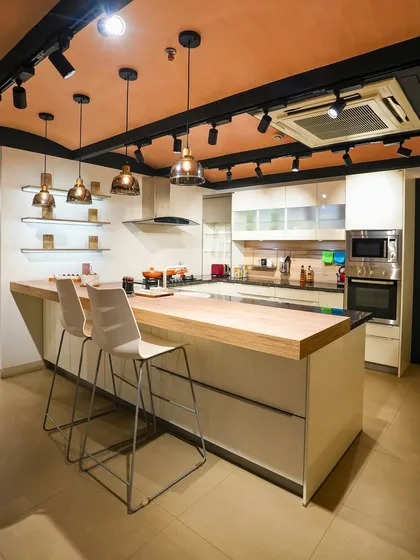 A modern, handleless kitchen display in Kolkata with a light wood breakfast bar, perfect for casual dining and socializing.