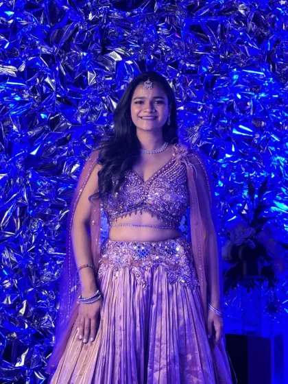Posing in my shimmering Sangeet lehenga against a textured blue wall, capturing the glamour of the evening.