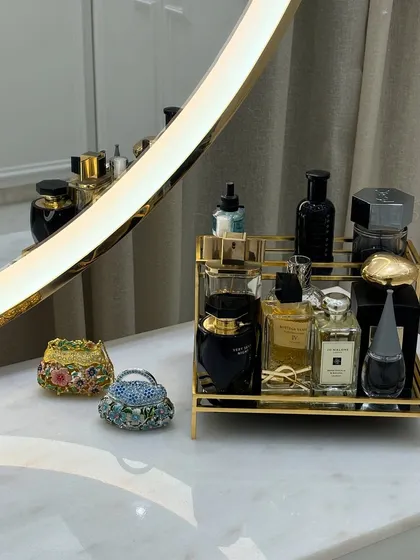 An elegant arrangement on a vanity top. A golden tray corrals perfumes, while miniature decorative bags add a touch of personal style.