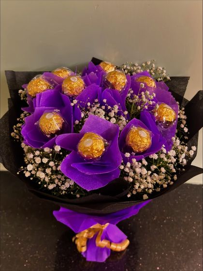 A full-length shot of the purple Ferrero Rocher bouquet, showcasing its elegant wrapping and golden ribbon tie.