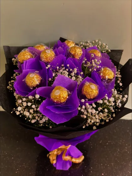 A full-length shot of the purple Ferrero Rocher bouquet, showcasing its elegant wrapping and golden ribbon tie.