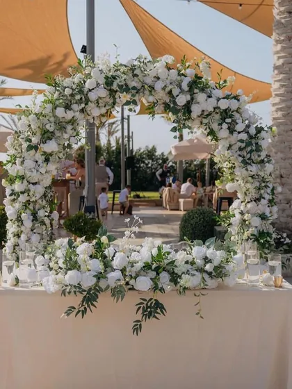 A beautiful circular floral arch at an outdoor venue, creating a perfect frame for the couple's table or a stunning photo backdrop.