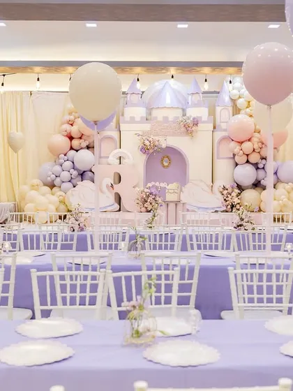 A wide view of Radha's "ONEderland" first birthday, where a pastel castle backdrop, swan props, and lavender tables created a fairytale setting fit for a princess.