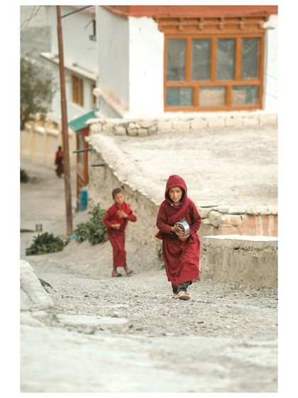 A little monk in his traditional red robes walks through the alleys of Karsha village.