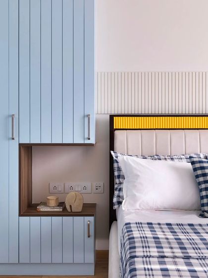 In this bedroom, a pop of yellow on the headboard feels like a burst of sunshine against the soothing powder blue wardrobe and checkered bedding. It's a playful yet sophisticated use of color.