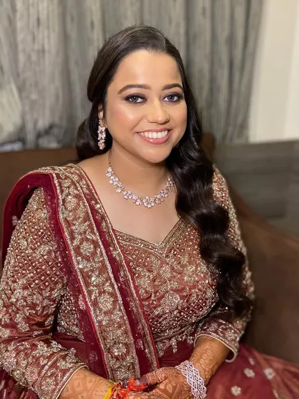All set for Sangeet with this beautiful bride. Her makeup features a soft smokey eye and a flawless base, complementing her maroon and gold outfit.