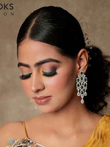 A softer angle of the colorful party makeup. With her eyes looking down, you can appreciate the blend of the teal and yellow eyeshadows on the lid. This look is perfect for someone who loves to be creative with their makeup.
