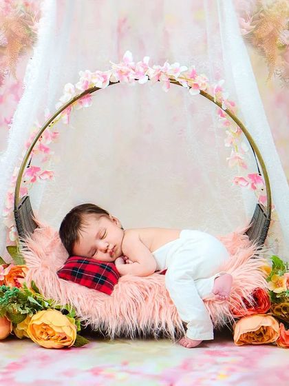 A sleeping newborn rests peacefully in a beautiful floral swing prop. This dreamy setup creates a magical, fairytale-like portrait.