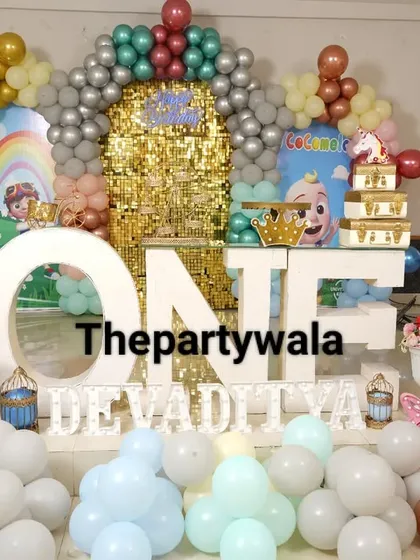 A grand Cocomelon first birthday party with a large "ONE" sign and a gold shimmer wall. This is a very glamorous and exciting setup for a big celebration.
