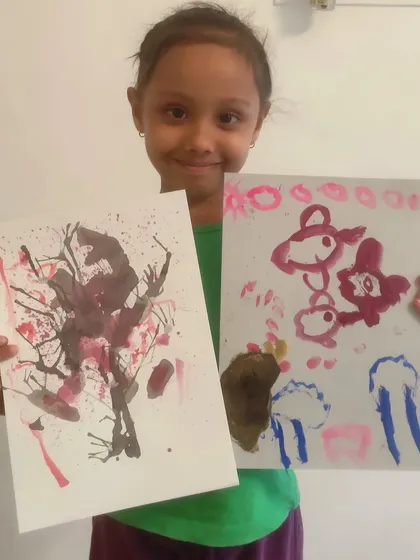 A duplicate image of a student displaying two of her creations, including an abstract cherry blossom tree.