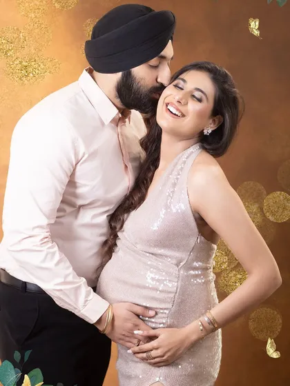The joy of expecting, shared between partners. This candid moment captures a genuine laugh, showcasing the love and excitement of the journey. The glamorous sequin gown adds a touch of sparkle to this beautiful memory.