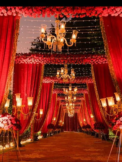 For a truly royal and traditional feel, nothing compares to classic red. This grand passageway uses rich red draping, intricate floral work, and rows of elegant chandeliers to build a sense of opulence and anticipation.