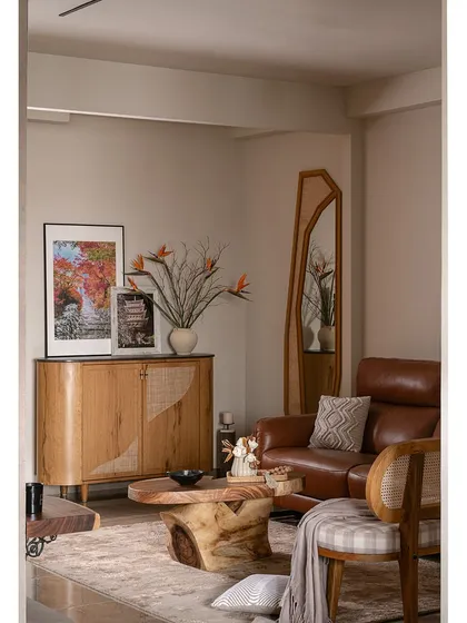 This view shows the foyer's shoe rack with rustic veneer and cane shutters, adding warmth and texture. An organic-shaped mirror enhances the sense of space, making the entryway feel more open and inviting.
