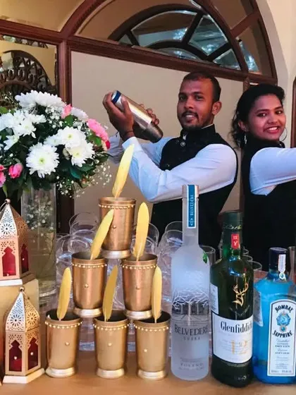 Flair and function combined. My bartenders showcase their skills with cocktail shakers at a beautifully arranged Sufi bar, complete with premium spirits, fresh flowers, and stacks of ornate brass glasses.