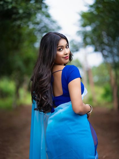 A back view of a model in a blue saree, showing the flow of the fabric and her graceful turn.