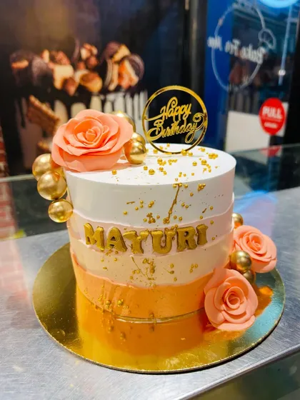 A beautiful orange ombre cake decorated with peach-colored roses and gold accents.