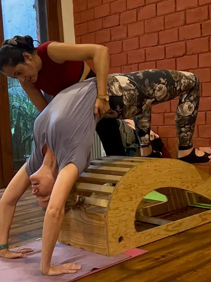 My approach to teaching is hands-on and personalized. Here, I am helping a student safely deepen her Chakrasana (Wheel Pose) using a spine corrector prop. This is how we build strength and flexibility with proper alignment, ensuring you learn the correct technique from day one.