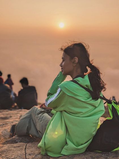 A trekker enjoying the beautiful sunrise from the peak of Skandagiri.