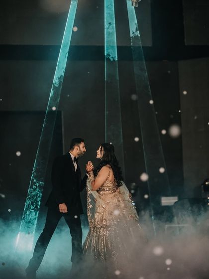 A romantic dance under the spotlight. The dramatic lighting and smoke effects create a cinematic and intimate feel for the couple's first dance at their reception.