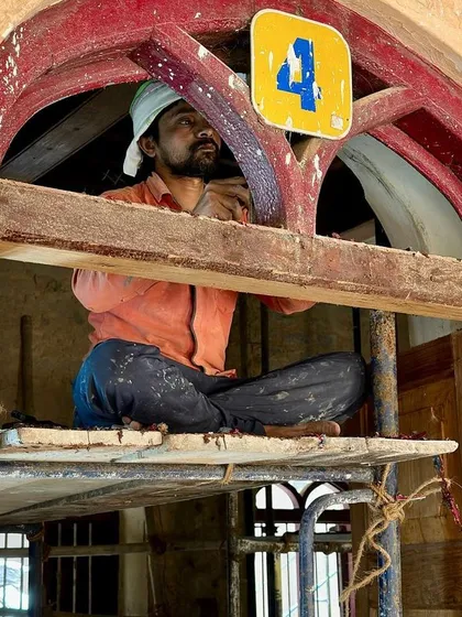 A repeat image of a worker in the window transom, focusing on the detailed woodwork.