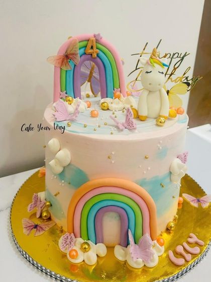 A magical two-tier unicorn cake with rainbows and butterflies for a 4th birthday celebration.