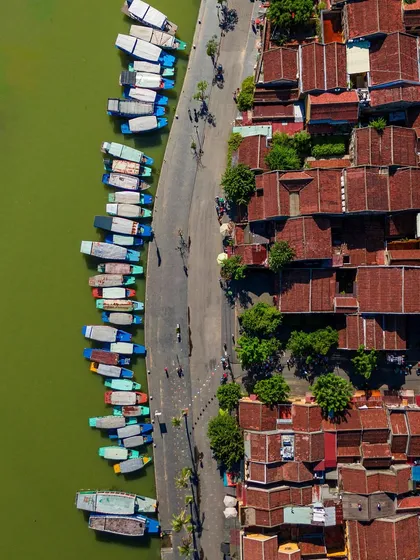A top-down view of the ancient town of Hoi An, with its iconic yellow walls and traditional architecture, situated by the river.